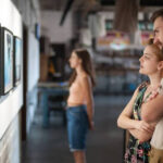 Two event attendees look at art available at an art gallery fundraiser