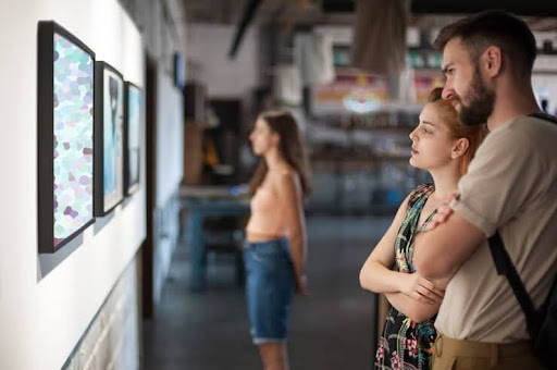 Two event attendees look at art available at an art gallery fundraiser