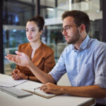 Two employees looking at a computer screen and talking